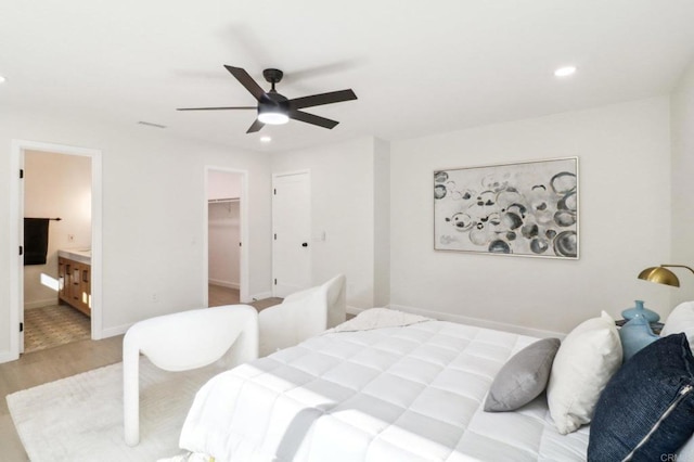 bedroom with connected bathroom, a spacious closet, light hardwood / wood-style floors, and ceiling fan