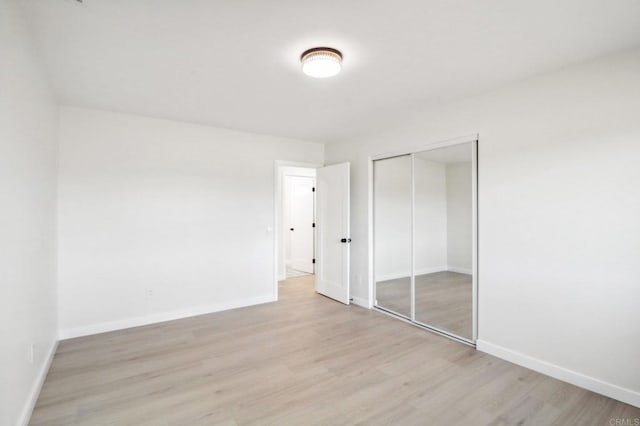 unfurnished bedroom featuring light wood-type flooring and a closet