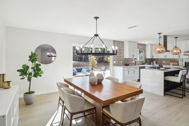 dining space with a notable chandelier and light wood-type flooring