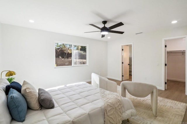 bedroom with ceiling fan, a spacious closet, and light hardwood / wood-style flooring