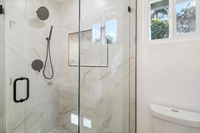 bathroom with a shower with shower door and toilet