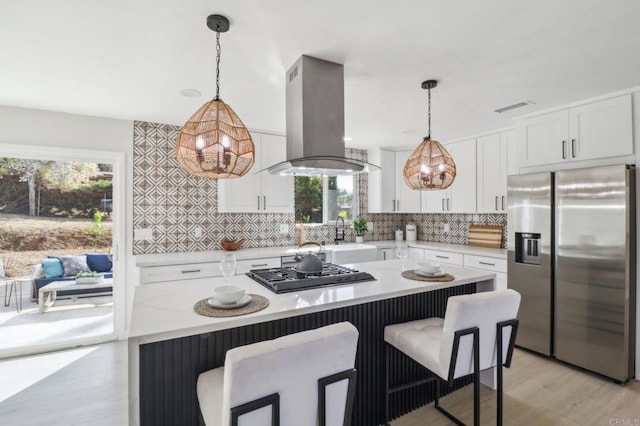 kitchen featuring white cabinetry, island range hood, stainless steel appliances, and decorative light fixtures