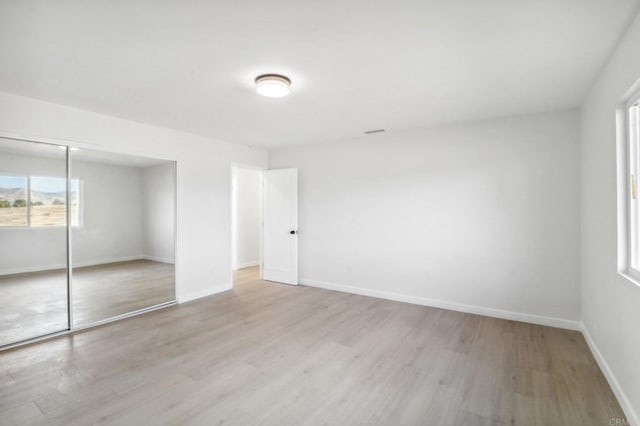 unfurnished bedroom featuring light wood-type flooring and a closet