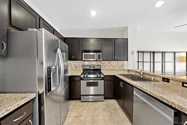 kitchen featuring light stone countertops, appliances with stainless steel finishes, sink, and backsplash