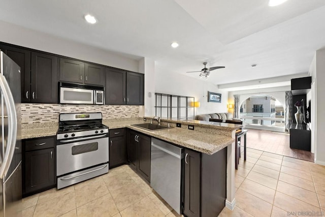 kitchen featuring sink, light tile patterned floors, stainless steel appliances, light stone countertops, and kitchen peninsula