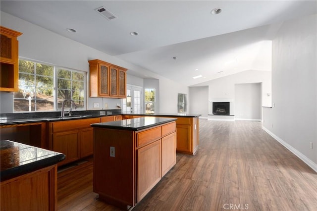 kitchen with lofted ceiling, sink, dark wood-type flooring, and a kitchen island