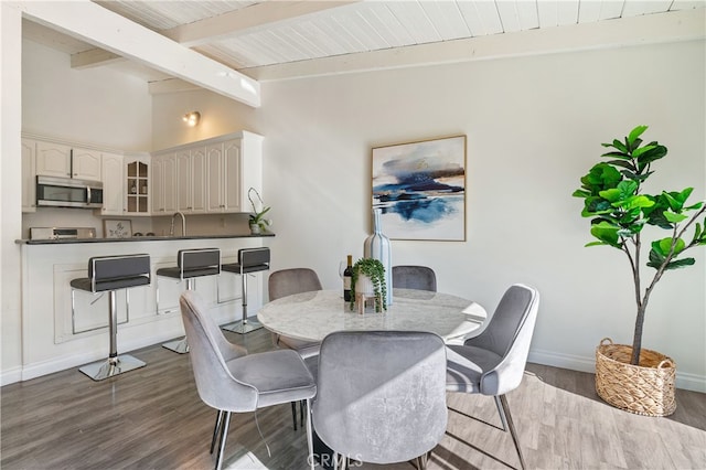 dining area with dark hardwood / wood-style floors, vaulted ceiling with beams, and wooden ceiling