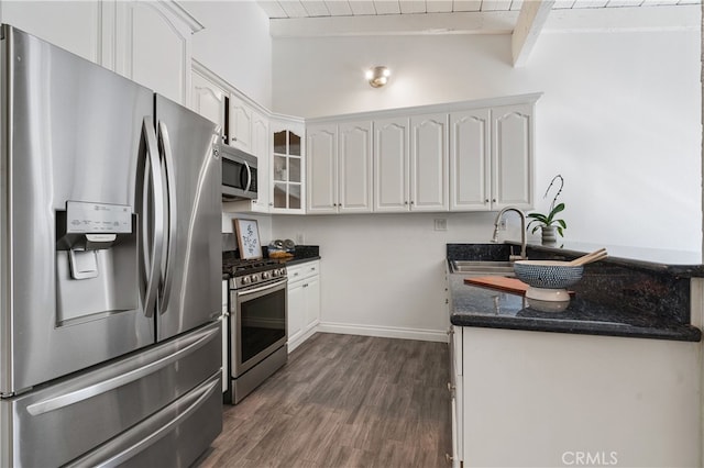 kitchen featuring sink, appliances with stainless steel finishes, dark hardwood / wood-style floors, dark stone counters, and white cabinets