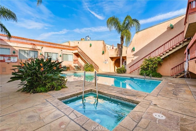 view of swimming pool with a hot tub and a patio area