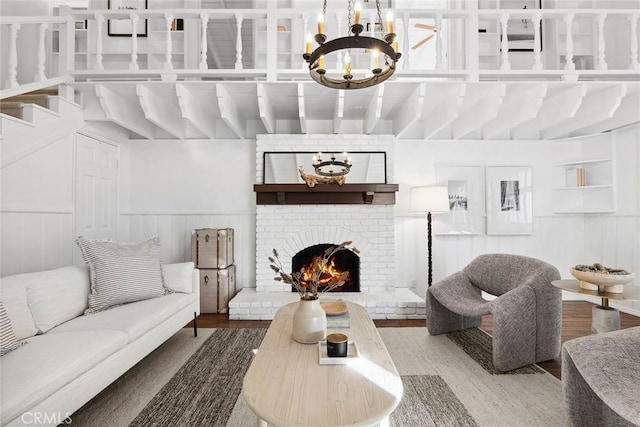 living room featuring an inviting chandelier, wood-type flooring, and a brick fireplace