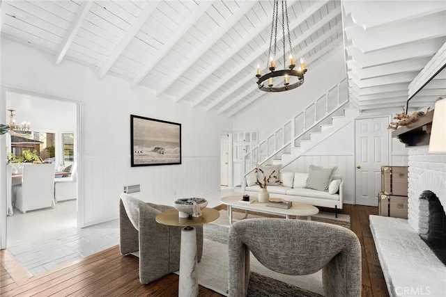 dining room featuring an inviting chandelier, hardwood / wood-style floors, a brick fireplace, and vaulted ceiling with beams