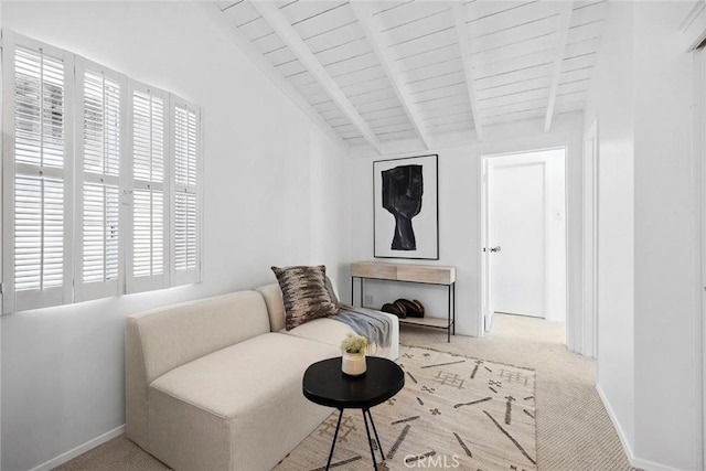 sitting room featuring lofted ceiling with beams and light carpet