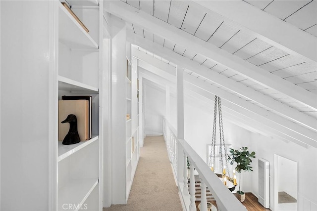 corridor with light colored carpet, wooden ceiling, and beamed ceiling