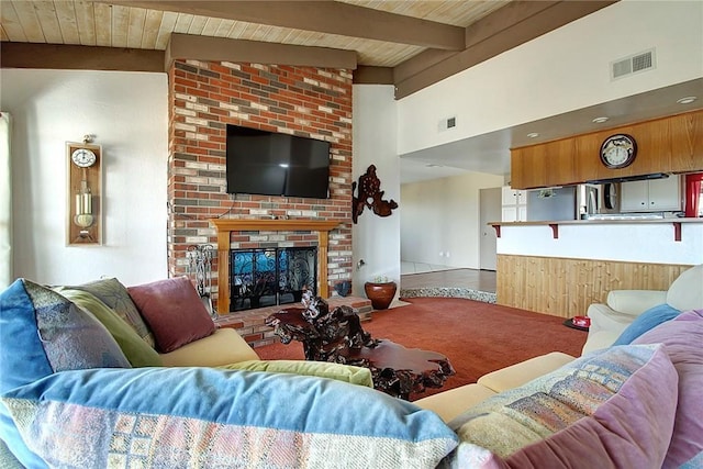 carpeted living room with a brick fireplace, wood ceiling, and lofted ceiling with beams