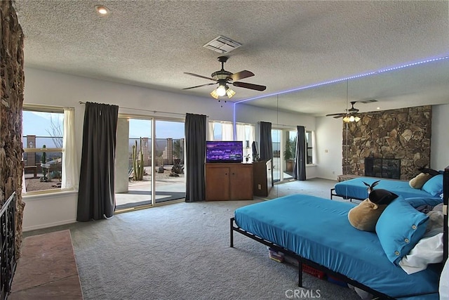 carpeted bedroom with multiple windows, a stone fireplace, access to outside, and a textured ceiling