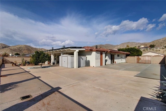 view of front of home featuring a shed, a mountain view, and a patio area