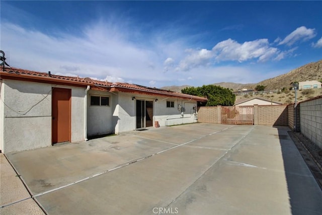 back of property with a mountain view and a patio area