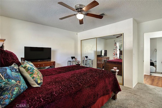 bedroom with ceiling fan, light carpet, a textured ceiling, and a closet