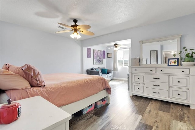 bedroom featuring ceiling fan, dark hardwood / wood-style floors, and a textured ceiling