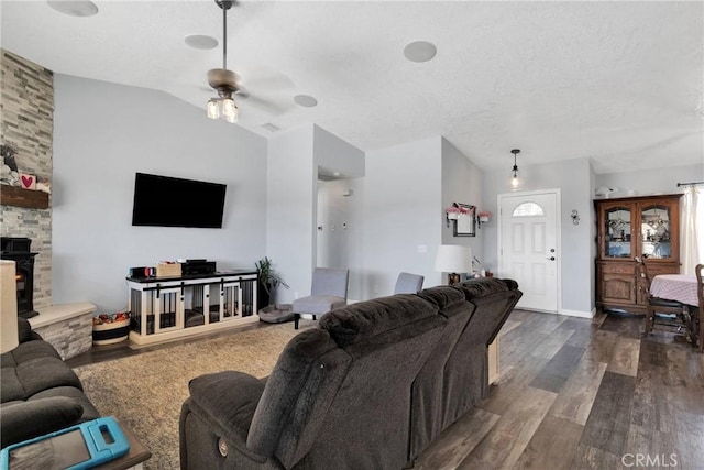 living room featuring ceiling fan, dark hardwood / wood-style floors, vaulted ceiling, and a fireplace