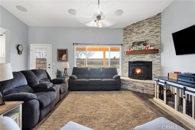 living room with a stone fireplace, dark wood-type flooring, and ceiling fan