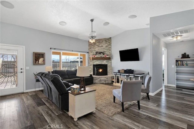 living room featuring a stone fireplace, vaulted ceiling, and dark hardwood / wood-style floors