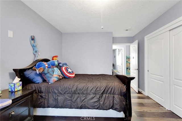 bedroom with dark hardwood / wood-style floors, a closet, and a textured ceiling