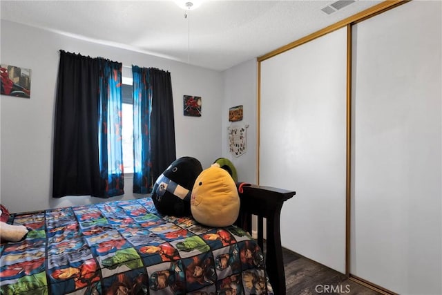 bedroom with dark hardwood / wood-style flooring and a closet