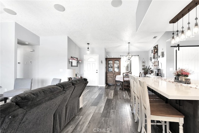 living room featuring a barn door, dark wood-type flooring, and a textured ceiling