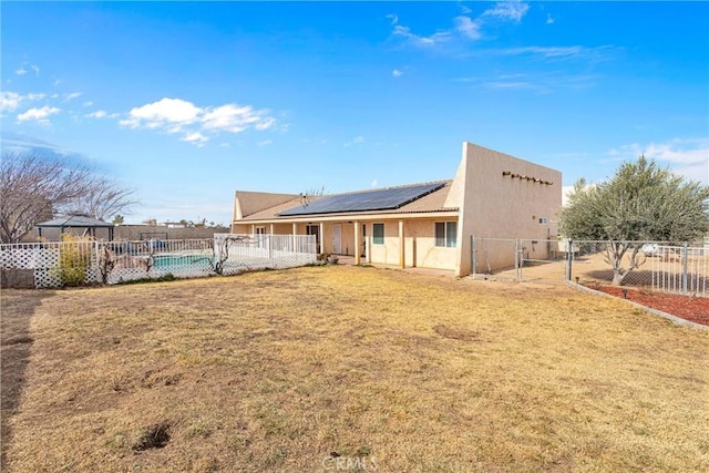 rear view of property with a fenced in pool, a yard, and solar panels