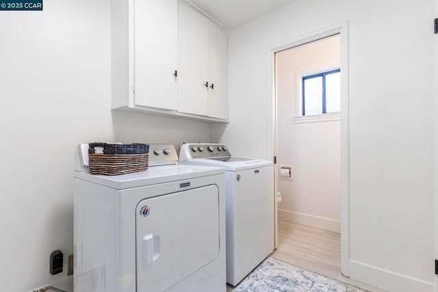 washroom featuring cabinets, washer and dryer, and light hardwood / wood-style flooring