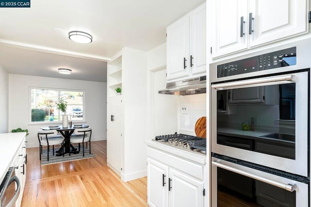 kitchen with white cabinetry, appliances with stainless steel finishes, light hardwood / wood-style floors, and decorative backsplash