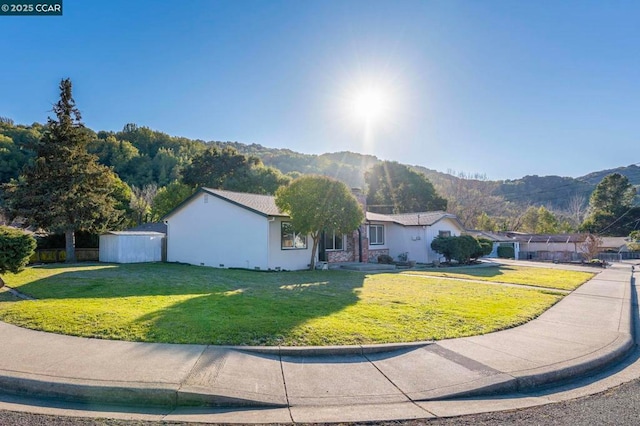 ranch-style house with a storage shed, a mountain view, and a front lawn