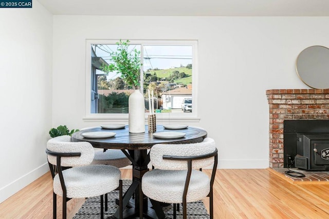 dining space with hardwood / wood-style floors and a wood stove