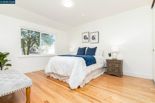 bedroom with wood-type flooring and vaulted ceiling