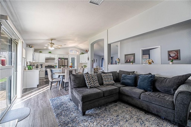 living room featuring lofted ceiling, a textured ceiling, ceiling fan, and light hardwood / wood-style flooring