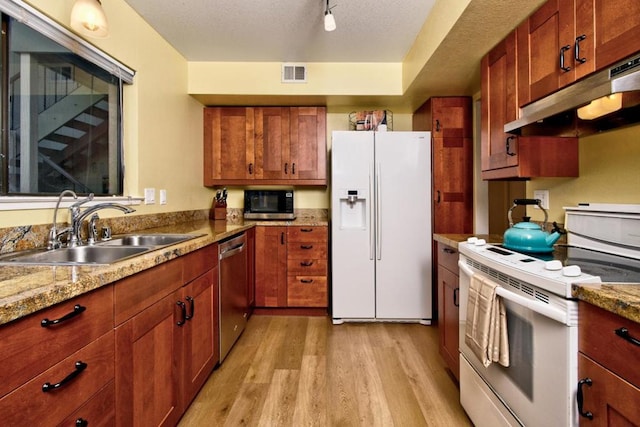 kitchen with sink, white appliances, light hardwood / wood-style floors, light stone countertops, and a textured ceiling