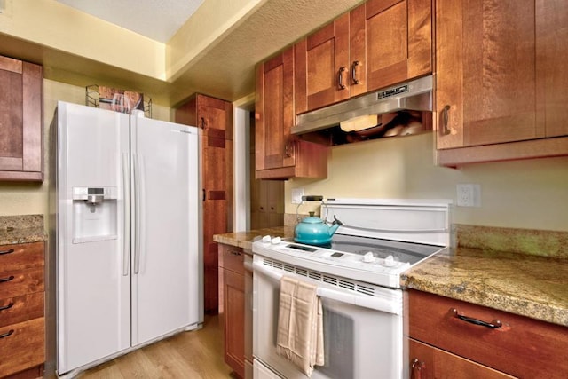 kitchen with light stone counters, white appliances, and light wood-type flooring