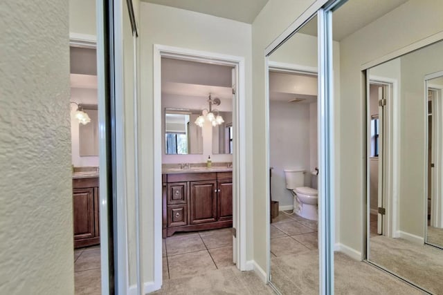 corridor with sink, light carpet, and a notable chandelier