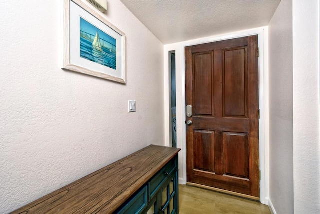 doorway featuring light hardwood / wood-style flooring and a textured ceiling