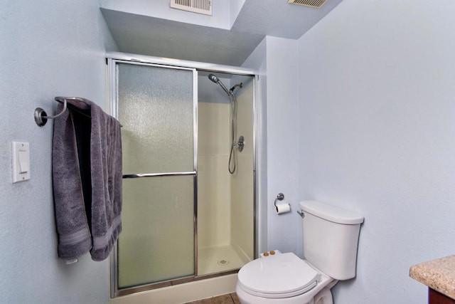 bathroom featuring a shower with door and toilet