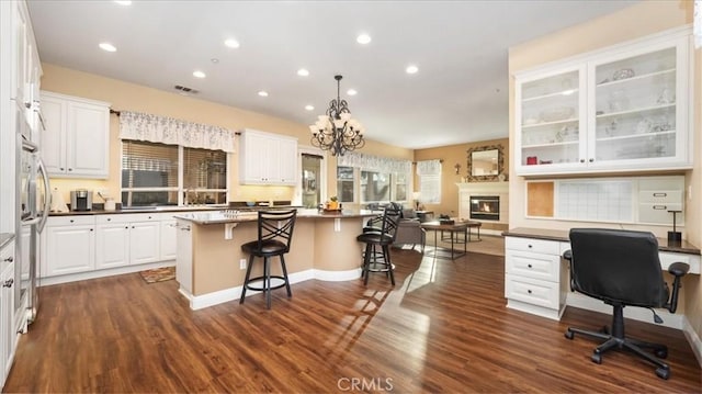 kitchen featuring pendant lighting, dark wood-type flooring, a breakfast bar, white cabinets, and a kitchen island