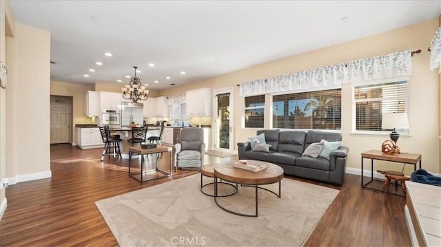 living room featuring dark wood-type flooring, a healthy amount of sunlight, and an inviting chandelier