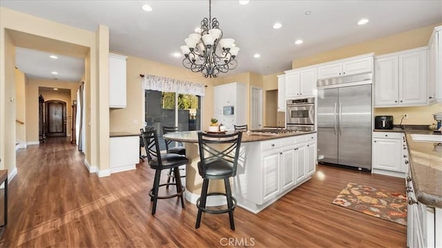 kitchen featuring a kitchen island, white cabinetry, a breakfast bar area, dark stone counters, and built in appliances