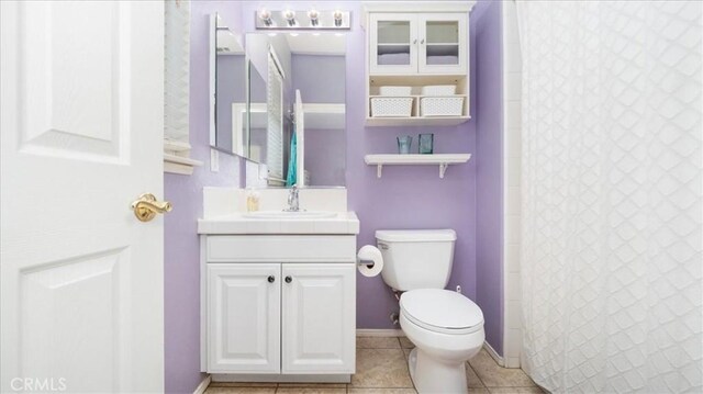 bathroom with tile patterned flooring, vanity, curtained shower, and toilet