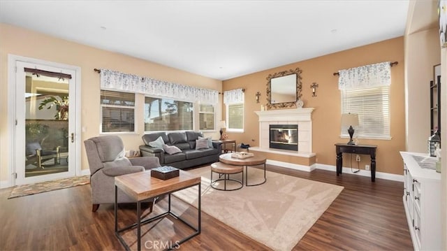 living room featuring a tile fireplace and dark wood-type flooring