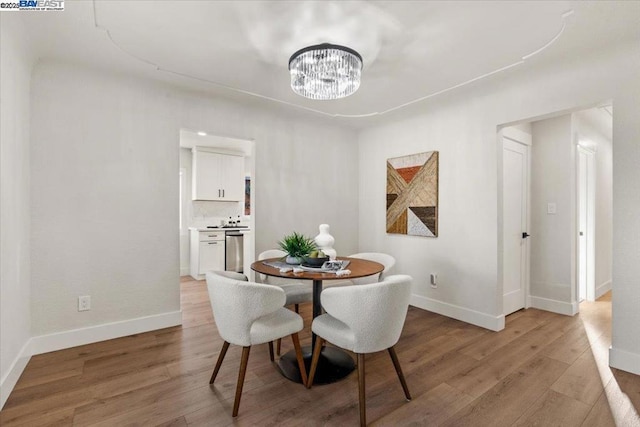 dining area featuring a notable chandelier and light wood-type flooring