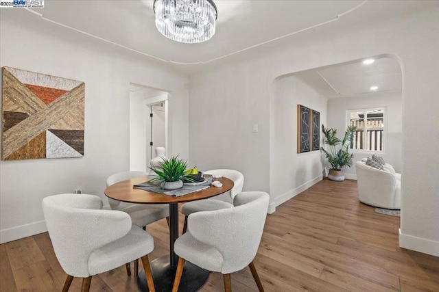 dining space featuring wood-type flooring and an inviting chandelier