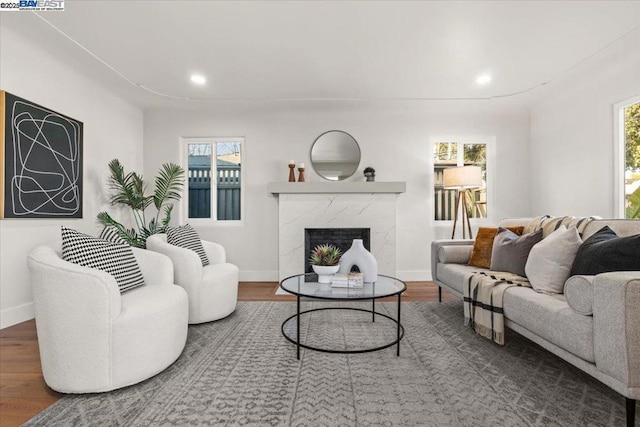 living room with a healthy amount of sunlight, a high end fireplace, and dark hardwood / wood-style flooring