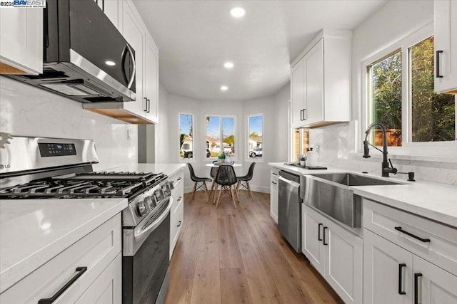 kitchen with white cabinetry, tasteful backsplash, stainless steel appliances, and light hardwood / wood-style flooring